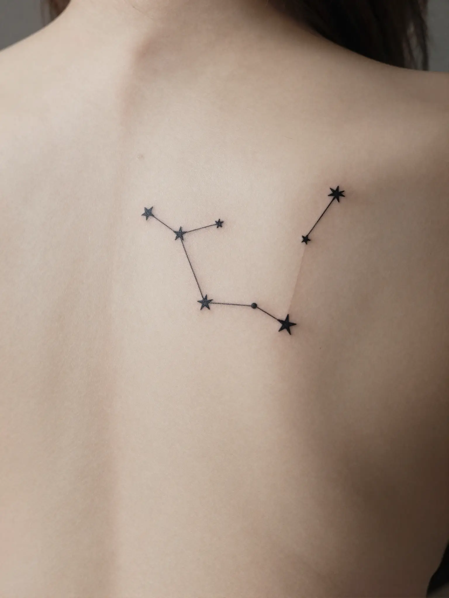Tatuagem feminina de constelação com pontos e linhas finas nas costas