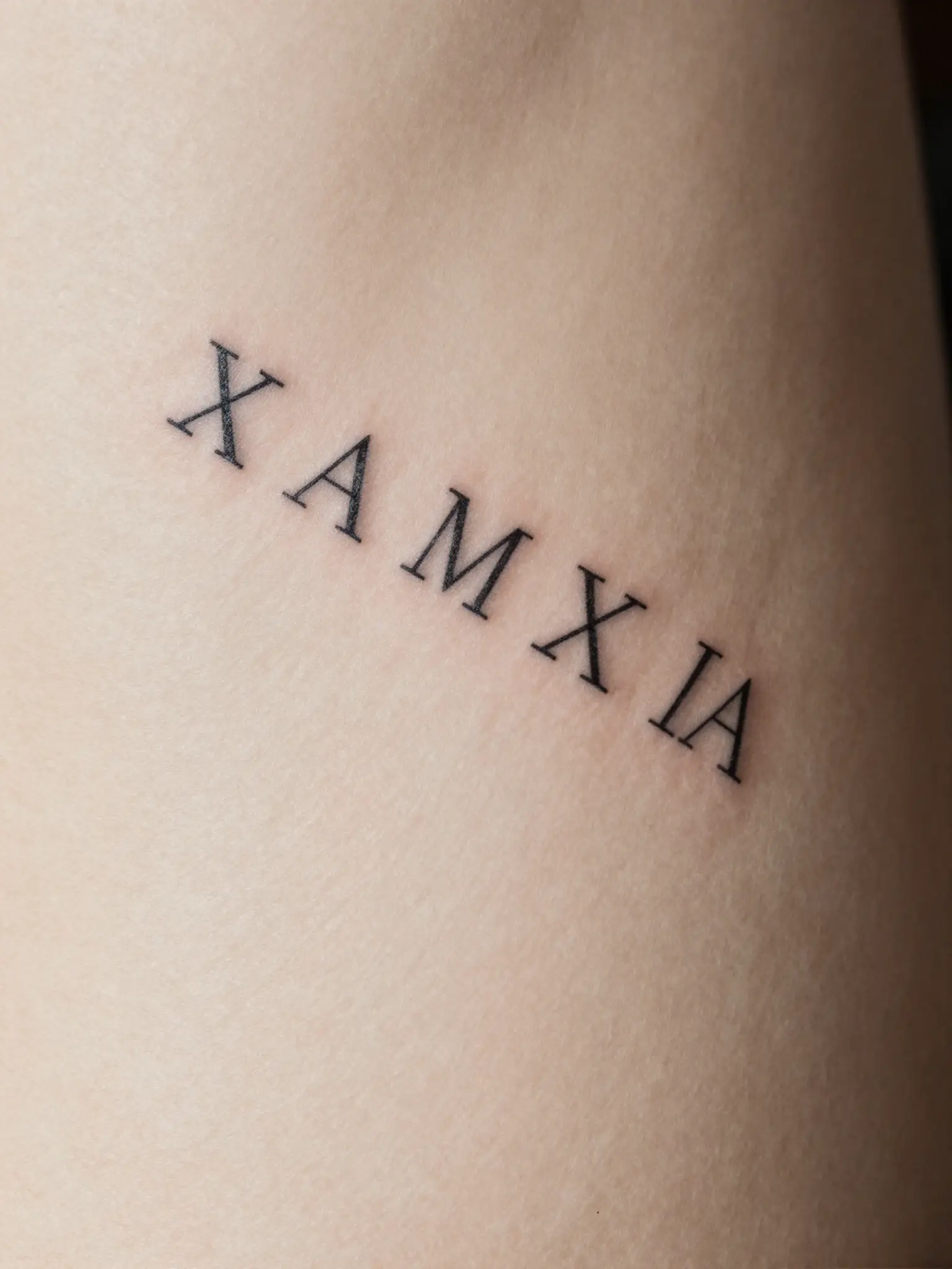 Tatuagem feminina de data em números romanos em traço fino